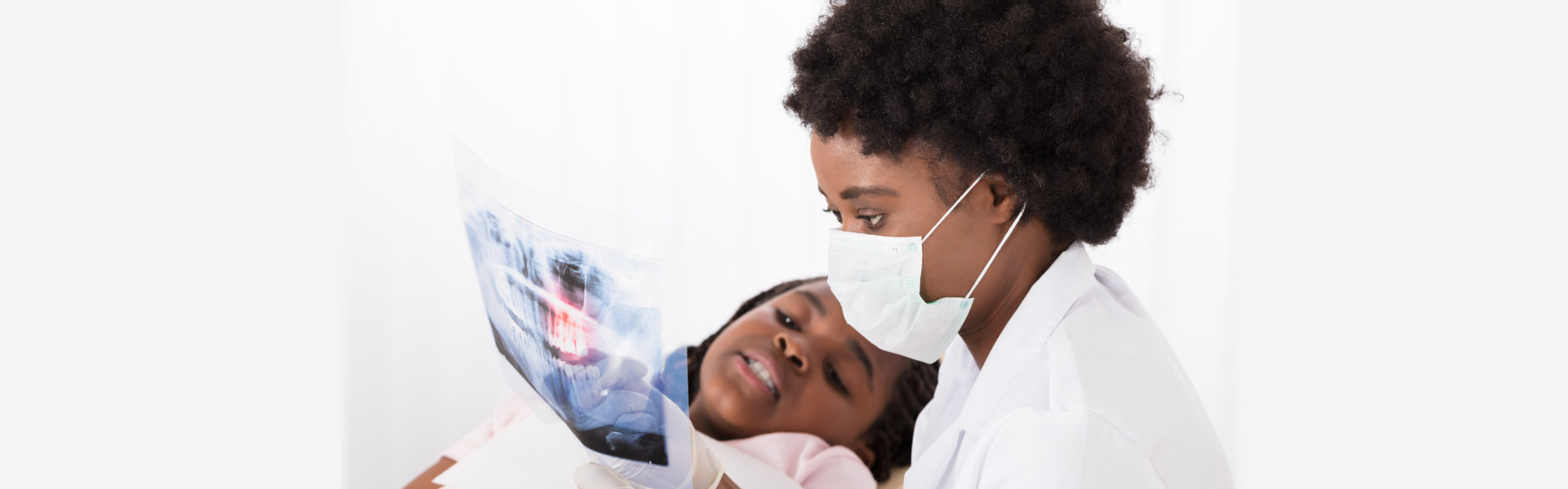 Close-up Of Dentists And Patient Looking At Patient's Teeth X-ray In Clinic