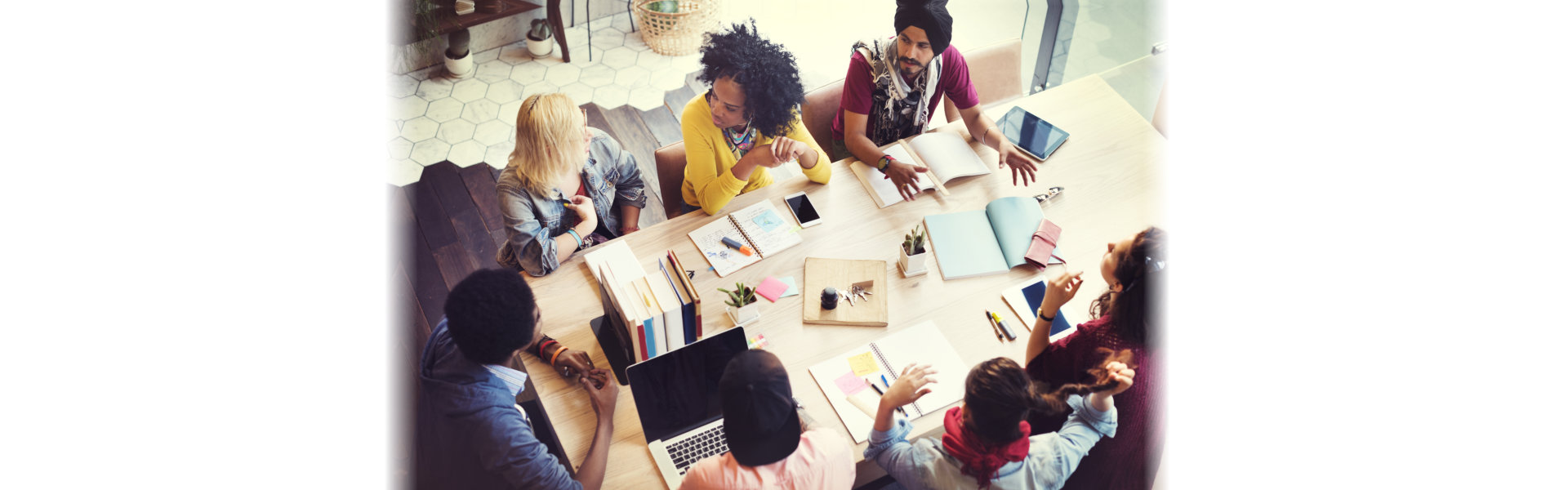 A team of professionals gathered around a table, each using laptops, promoting a productive and interactive work atmosphere